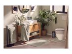 Bathroom with wooden vanity, white sink, black faucet, green towels, and plants.