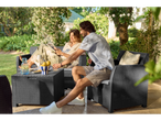 Couple relaxing on a dark grey wicker outdoor furniture set.