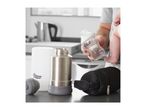 Tommee Tippee baby bottle, flask, and warmer on a kitchen counter with a parent holding a baby.