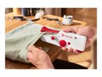 Hands using a red and white Singer handheld sewing machine on light green fabric.