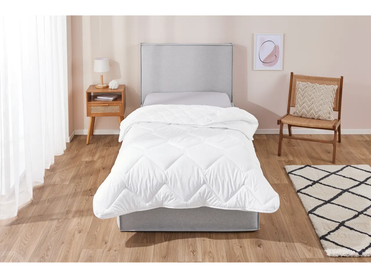 Bed with white duvet in a bright bedroom.