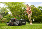Woman using a Parkside lawnmower in her garden.