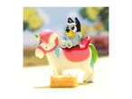 Bluey toy riding a unicorn toy with a small cake in front.