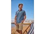 Man in blue polo shirt and beige shorts on a beach with a deckchair.