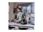 Man in kitchen preparing food with a food steamer and glass container.