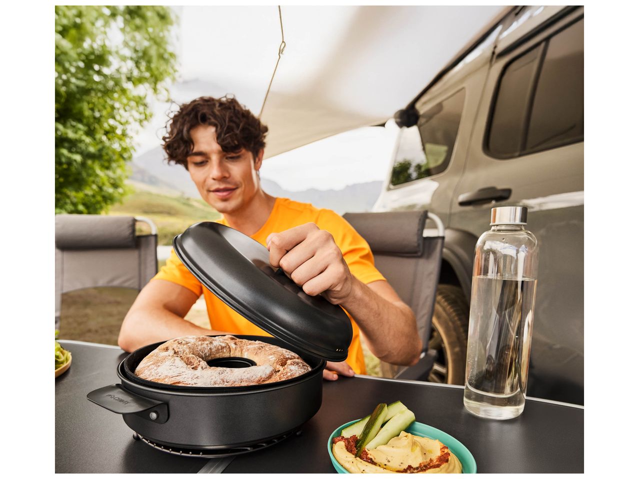 Un homme ouvre un plat à four Campingaz pour révéler un gâteau cuit au four.