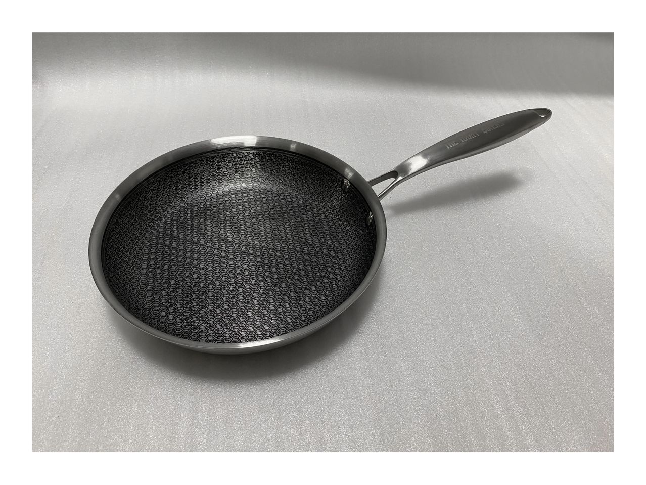 A stainless steel frying pan with a long handle.