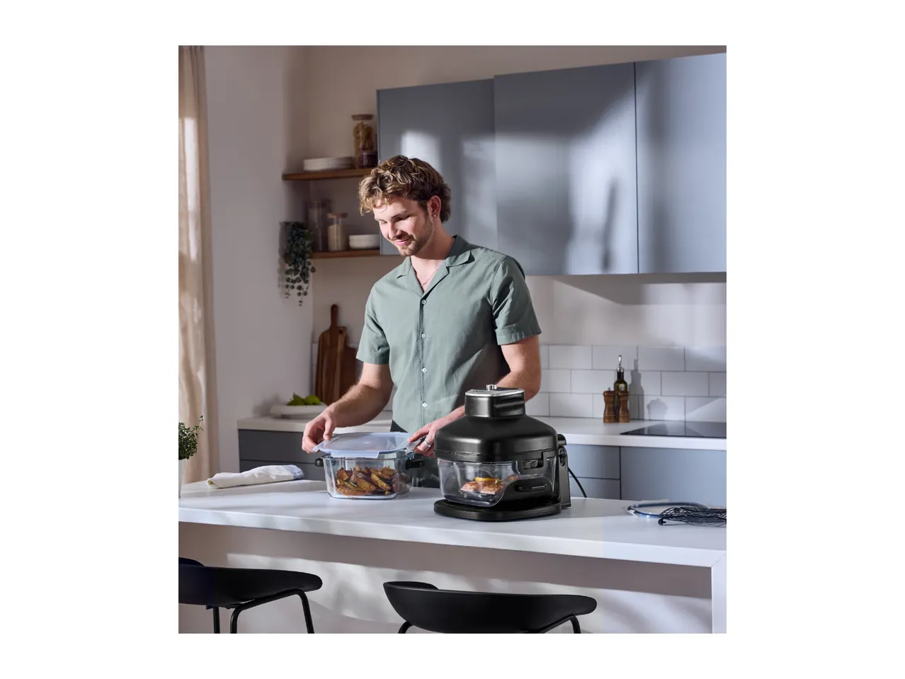 Man in kitchen preparing food with a food steamer and glass container.