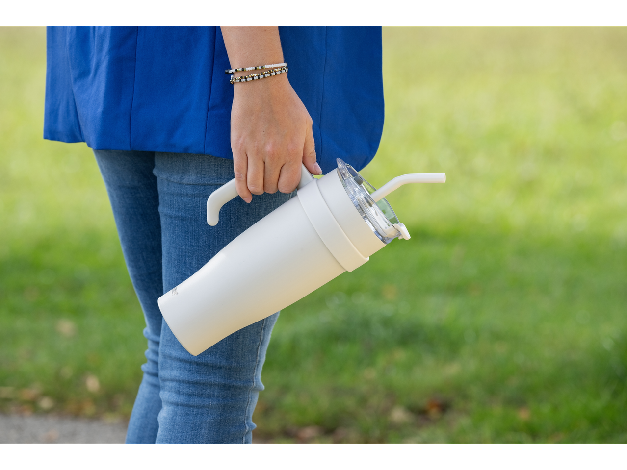 Woman holding a white tumbler with straw.