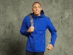 A man in a blue softshell jacket with a backpack looking to the right.