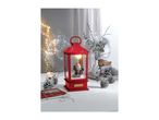Red Christmas lantern with Santa figurine, surrounded by pinecones, a candle, and gifts.