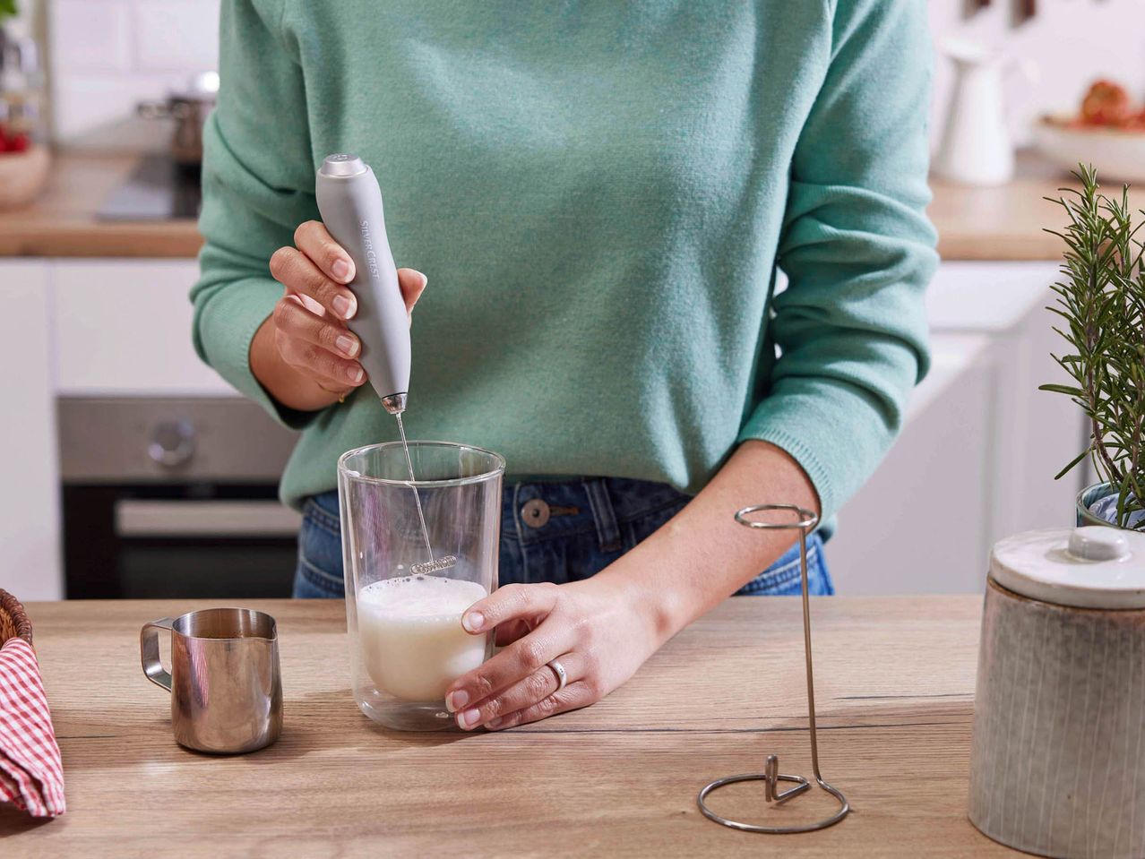 A person frothing milk with a SilverCrest milk frother in a glass.