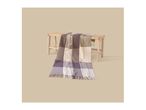 A striped throw blanket in shades of brown, beige, and purple draped over a wooden bench.