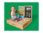 Girl playing in a wooden sandpit with a water wall and chalkboard with drawings.