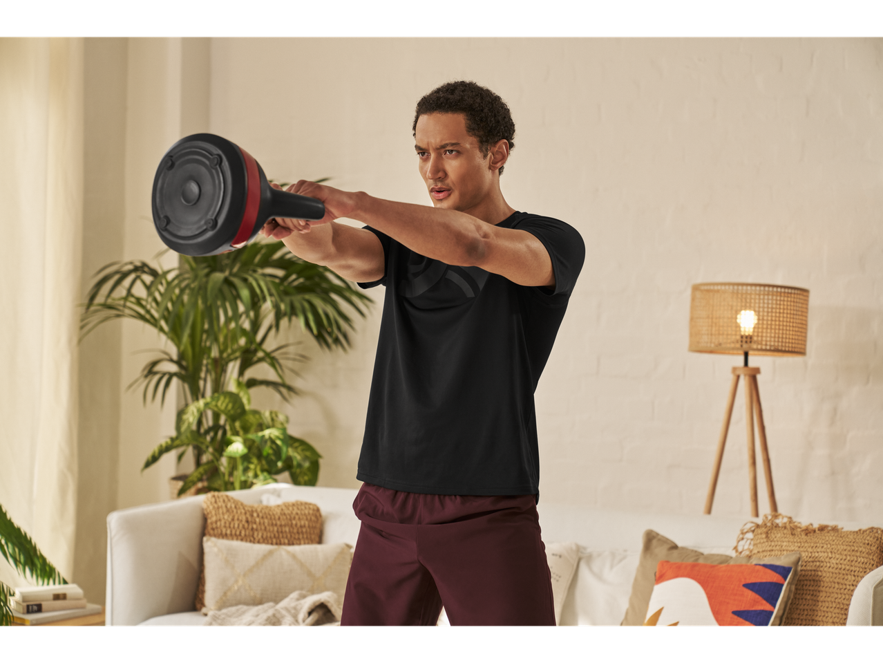 Un bărbat face exerciții cu o ganteră Bowflex SelectTech în sufragerie.