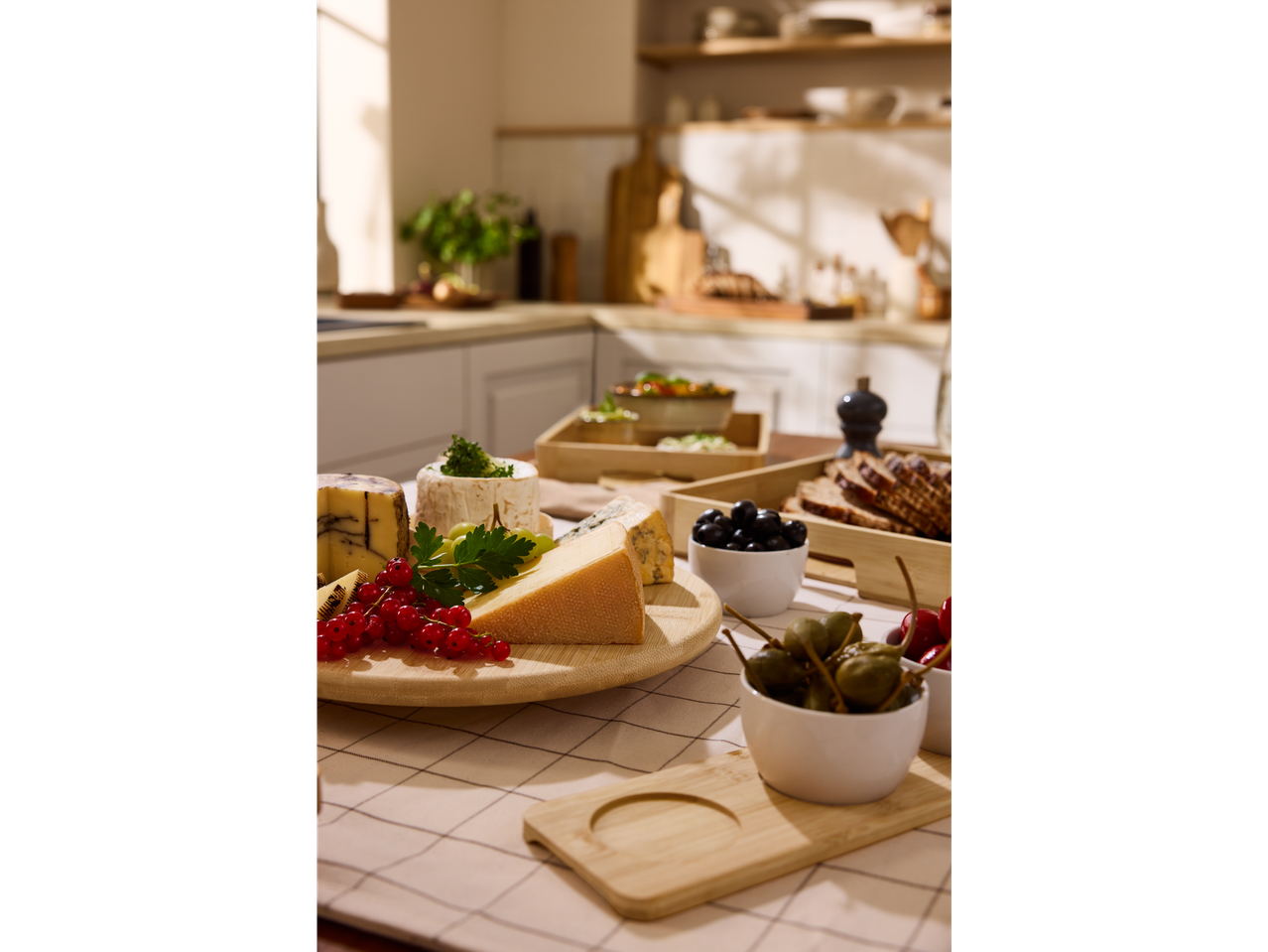 Bandeja giratória SILVERCREST® com queijos, frutas vermelhas e azeitonas numa cozinha.