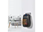 TRONIC® 600W Ceramic Plug Heater plugged into a wall socket, emitting heat, with a blurred living room in the background.