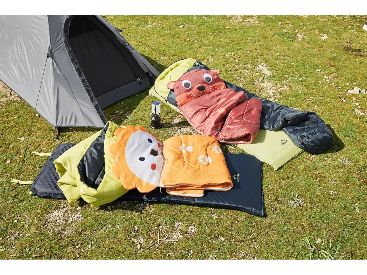 Sacchi a pelo Crivit per bambini con disegni di animali vicino a una tenda sull'erba.