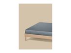 A grey fitted sheet on a light wooden bed frame against a beige background.