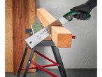 Eine behandschuhte Hand verwendet eine Parkside Handsäge, um ein Stück Holz auf einem Werktisch zu sägen.