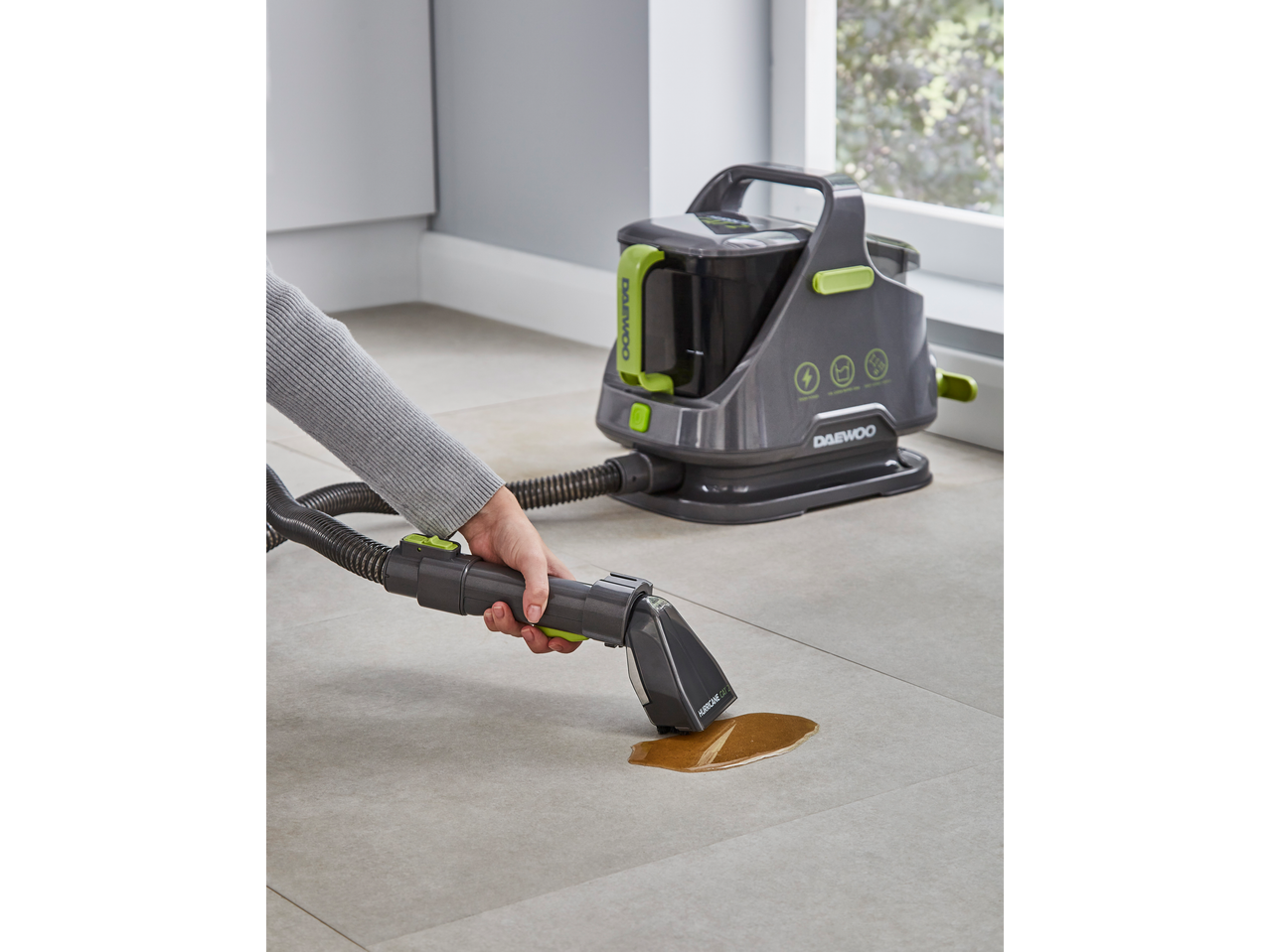 A person uses a Daewoo Hurricane Car 2 wet and dry vacuum cleaner to clean a spill on a tiled floor.