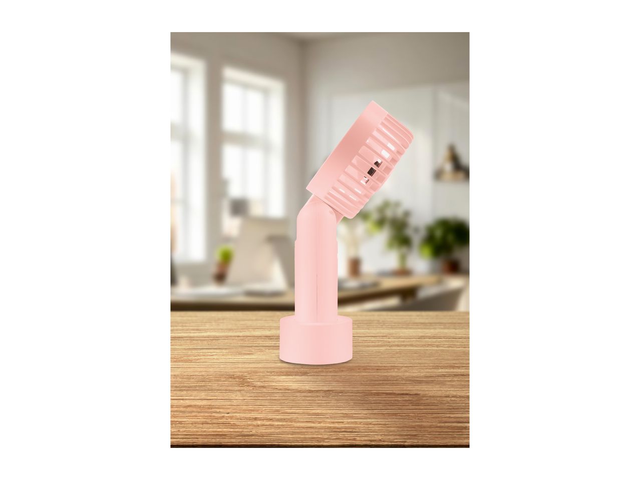Pink handheld fan on a wooden table in a bright room.