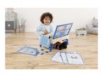 Happy child playing with a blue activity desk, puzzle, and coloring sheets on a wooden floor.
