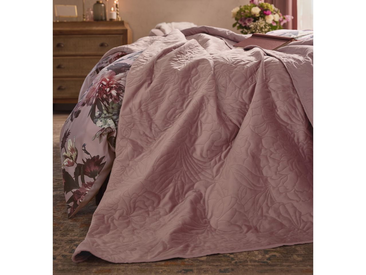Pink quilted bedspread with floral duvet cover in a cozy bedroom setting