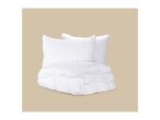 White ruched bedding set with a folded duvet and two pillows against a beige background