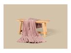 A soft pink fleece blanket draped over a rustic wooden bench.
