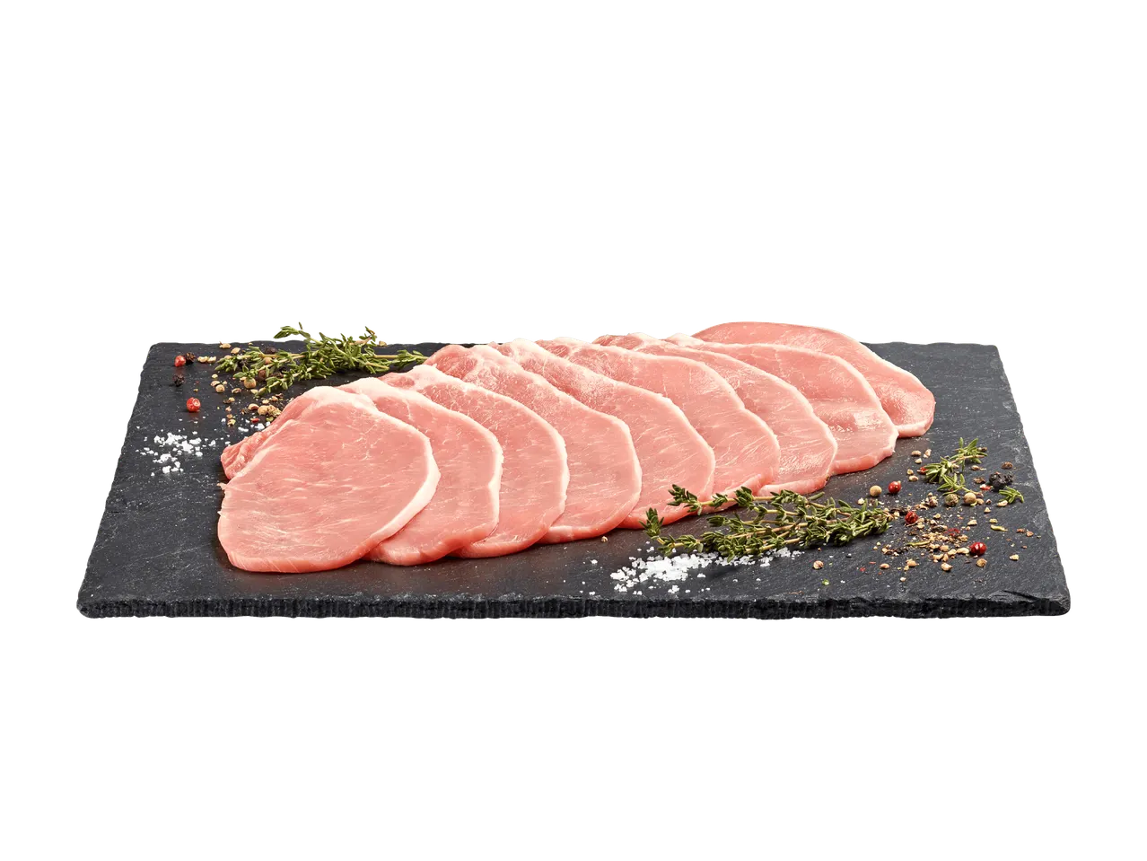 Tranches de viande de porc crues sur une planche en ardoise avec des herbes et des épices.