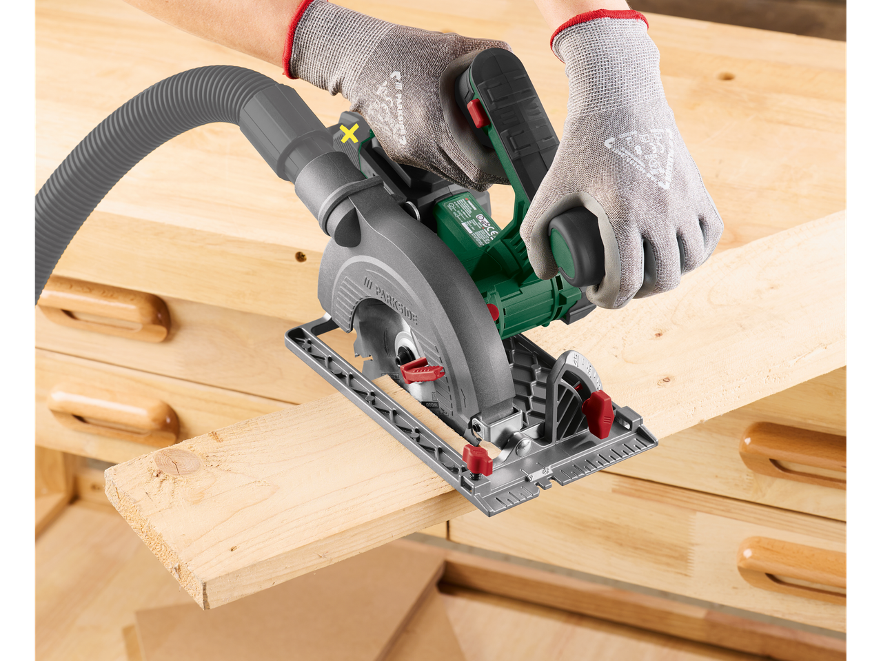 Parkside® cordless circular saw cutting a wooden plank on a workbench.