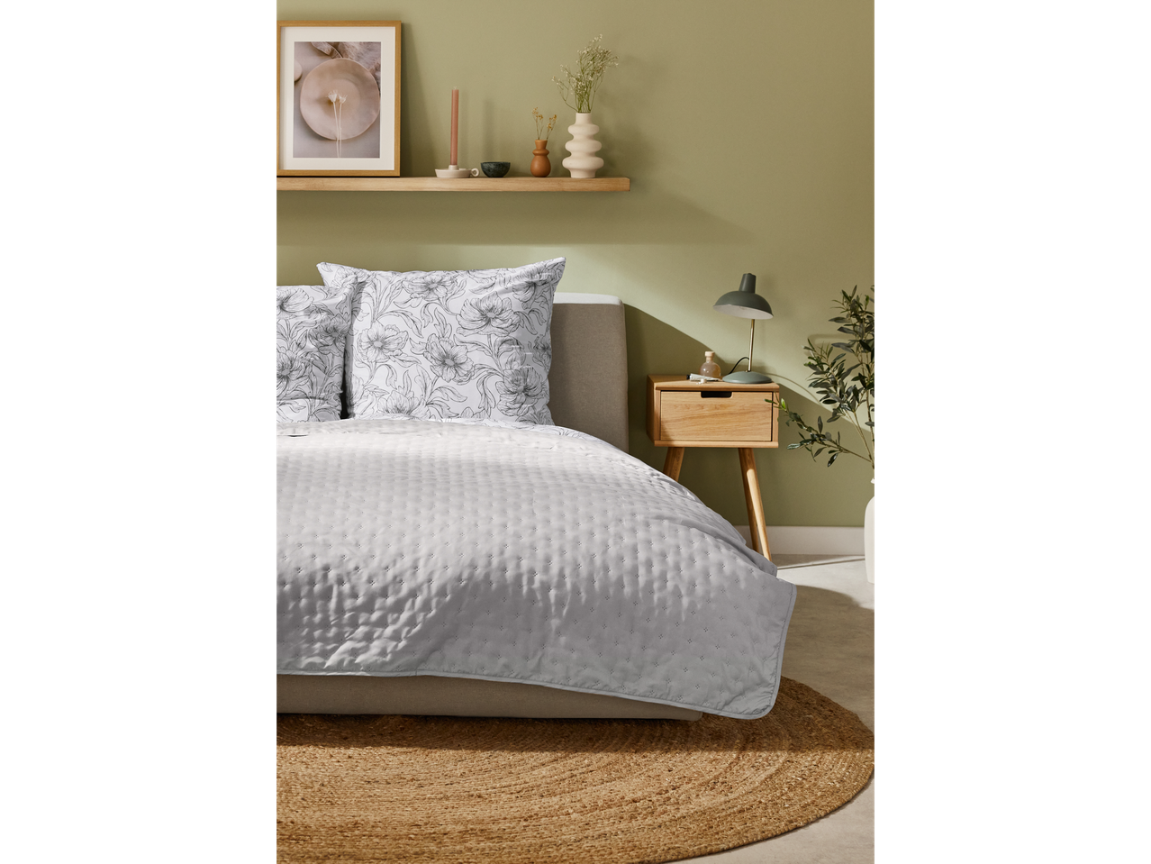 Cama com colcha e almofadas com padrão floral.