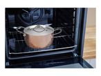 Copper pot with lid inside an open oven
