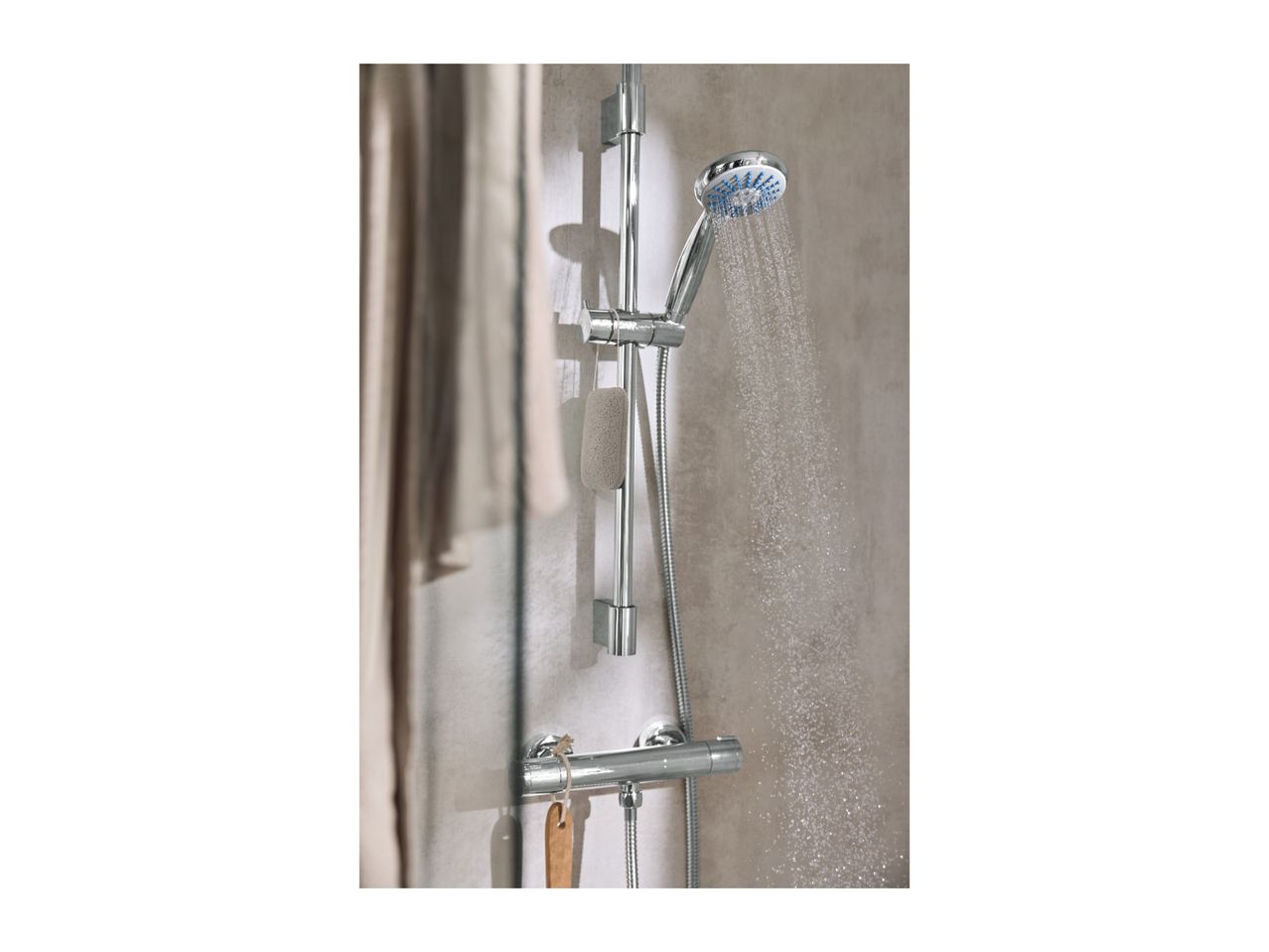 Chrome shower with running water, a sponge, and a wooden brush hanging on the rail.