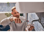 Man using pliers to fix a sink pipe.