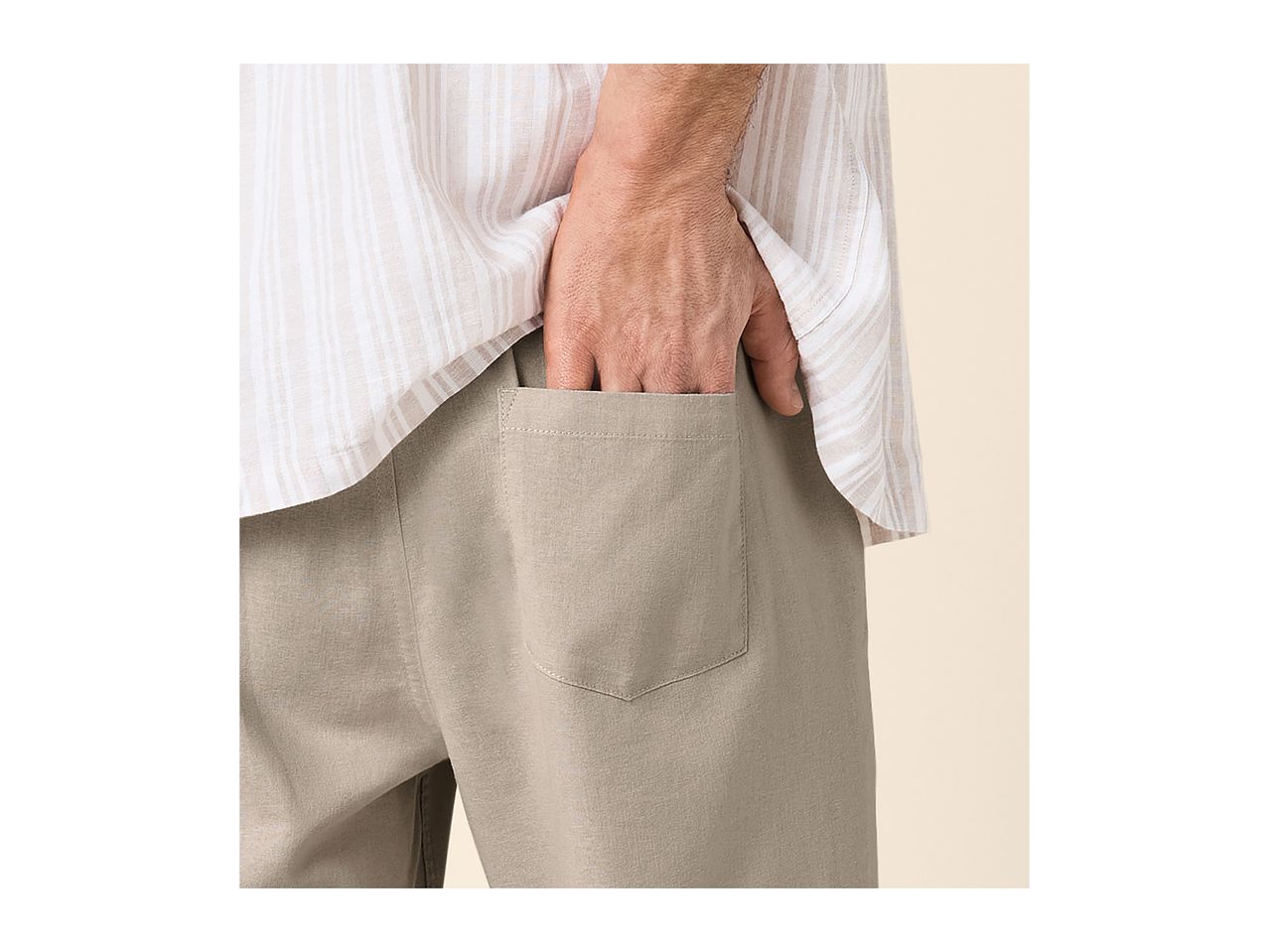 Man in a striped shirt and beige trousers with his hand in the pocket.