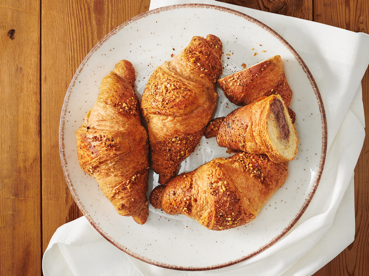 Кроасани с нуга пълнеж и лешникова поръска в бяла чиния.