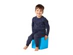 Smiling boy in navy blue pajamas with construction vehicle print, sitting on a blue cube.