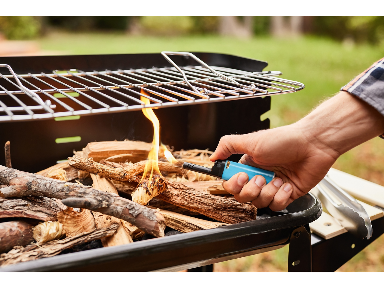 Lighting wood in a grill with a BIC lighter.
