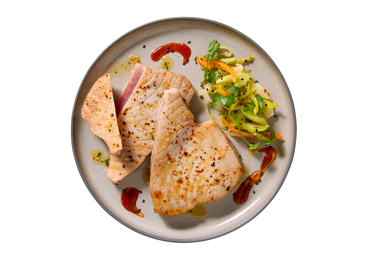 Bifes de atum selados com salada de vegetais e molho num prato.