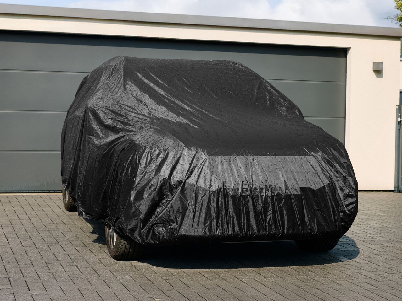 Black car cover on a car parked in front of a garage