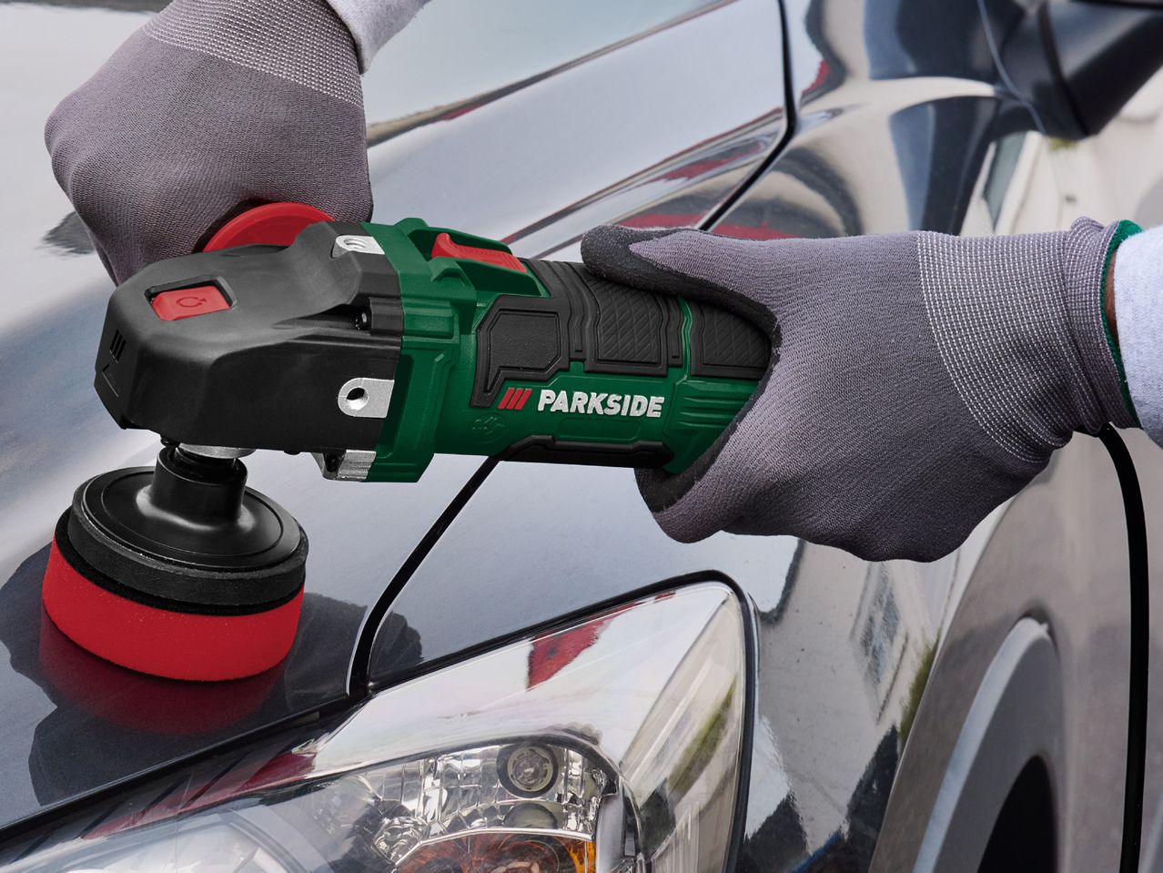 A person uses a Makita polisher to buff a car.