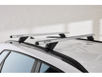 Silver car roof bars on a white car, with a white textured background.