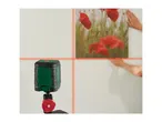 Cross line laser level projecting red lines on a wall to align a picture frame