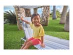 Smiling child on a striped sun lounger in a garden with palm trees.