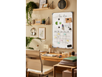 A home office desk with a whiteboard showing a weekly planner, markers, and accessories.