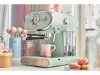 A mint green SilverCrest espresso machine brews coffee into a pink mug.