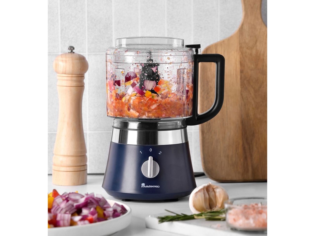 Un tritatutto Masterpro blu scuro trita verdure in una cucina moderna.