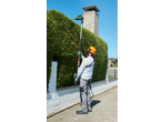 Man trimming a hedge with telescopic hedge shears.